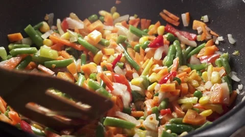 The process of cooking multicolored sliced vegetables in a frying pan Stock Footage 277969151