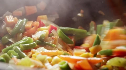 The process of cooking multicolored sliced vegetables in a frying pan Stock Footage 277969167