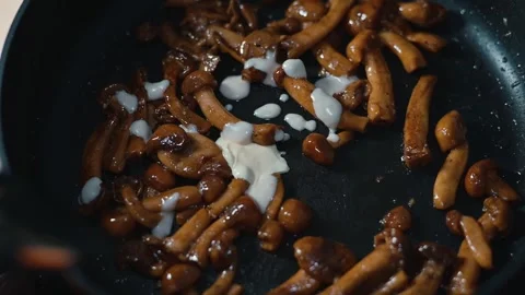 The process of cooking mushrooms in a pan. A person is preparing the dish by Video stock 339094547
