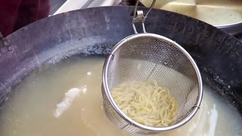 The process of cooking noodles in a large frying pan using a noodle maker Stock Footage 270347593