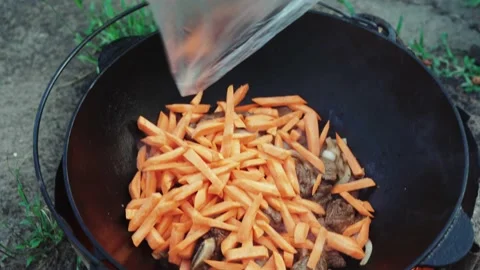 Process of cooking pilaf dish in outdoor - fry meat onion carrot. Video Stock Footage 160438145