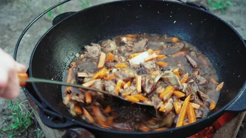 Process of cooking pilaf dish in outdoor with beef meat in a cauldron. Street Stock Footage 160438228