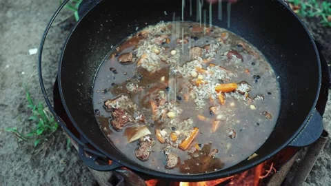 Process of cooking pilaf dish in outdoor with beef meat in a cauldron. Street Stock Footage 160438264