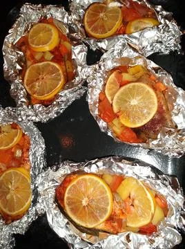 The process of cooking red trout fish with lemon and vegetables in foil Stock Photos