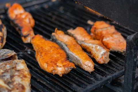 Process of cooking salmon steaks and mackerel fish on grill: street food concept Fotos de archivo