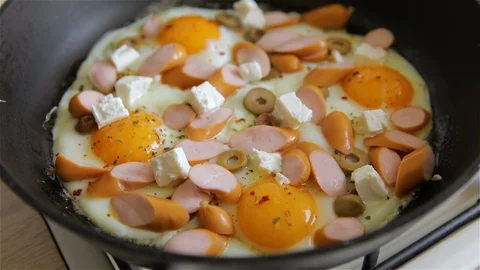The process of cooking scrambled eggs with sausages, olives and feta cheese. Stock Footage 126608825