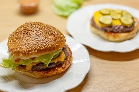Process of cooking self made burgers at home. Cheesy burger on a white plate Photos