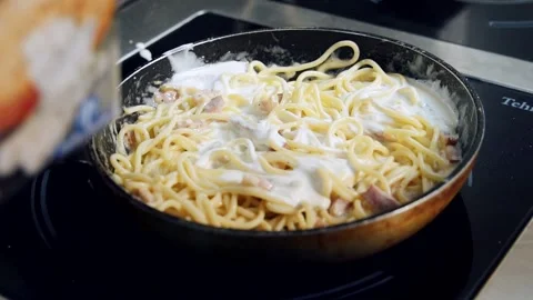 Process of cooking tasty pasta. Chef is pouring white sauce into spaghetti Stock Footage 236396974