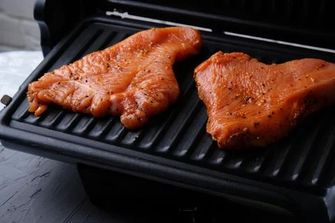 The process of cooking turkey fillets on the electric grill at home, close-up Photos