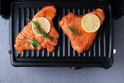 The process of cooking turkey fillets on the electric grill at home, close-up Stock-Fotos