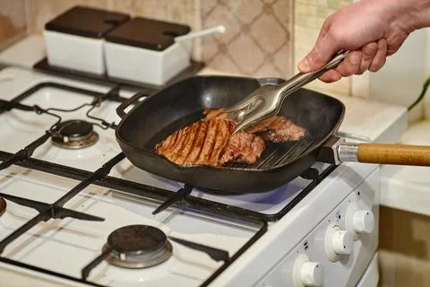 The process of cooking two beef steaks in frying pan, the hands of male chef  Stock Photos