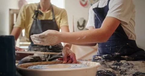 The process of creating a clay plate pottery master class woman teaches a young Stock Footage 154888196