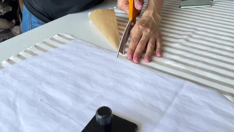 The process of creating clothes in the atelier. Tailor carefully cutting brown Stock Footage 312565667
