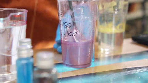 Process of creating colourful epoxy resin samples in plastic cup, workman in Stock-Footage 263136638