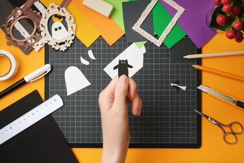 The process of creating a Halloween craft. Cut out the silhouette of a cat fr Stock Photos