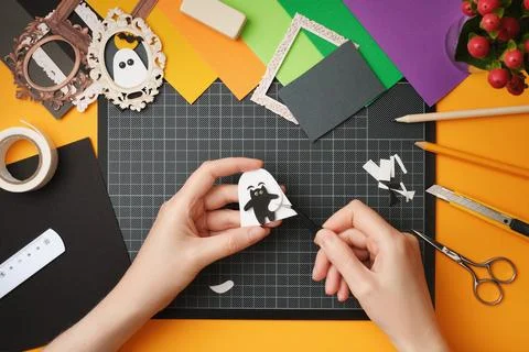 The process of creating a Halloween craft. Glue the silhouettes of the cat an Stock Photos