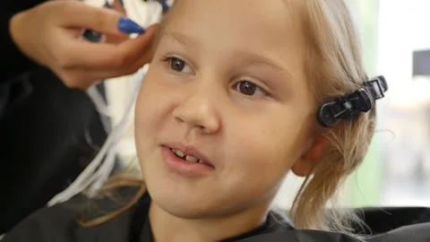 The process of creating a new hairstyle for a little beauty of adolescence in a  Stock Footage 221098467