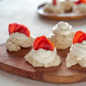The process of creating Pavlova dessert, decorating the meringue with strawbe Stock-Fotos