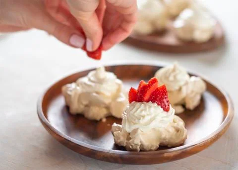 The process of creating Pavlova dessert, decorating the meringue with strawbe 库存照片