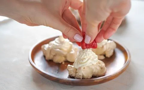 The process of creating Pavlova dessert, decorating the meringue with strawbe Stock Photos