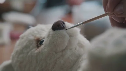 Process of creating a teddy bear: the master paints a toy nice smile Stock Footage 75492524