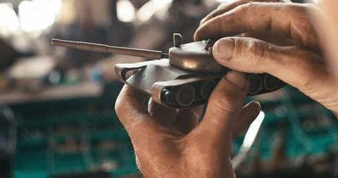 Process of creation of toy iron tank. The unknown man is inspacting it in his Stock Footage 93139264