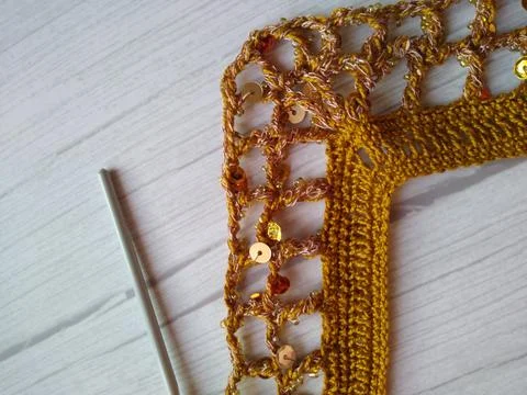 The process of crocheting from beads and sequins of golden color. Making a .. Stock Photos
