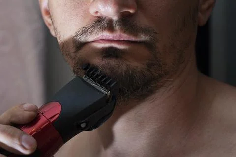 Process cutting beard handsome with trimmer. Young caucasian bearded man trim Stock Photos