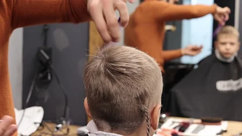The process of cutting a blond boy with a long braid in a chair in a barbershop Stock-Footage 146696620