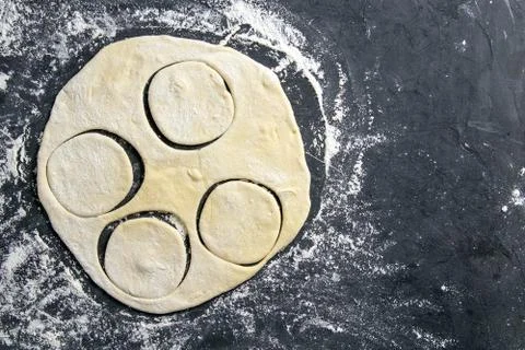 The process of cutting circle from the dough on a dark background. Top views  Stock Photos