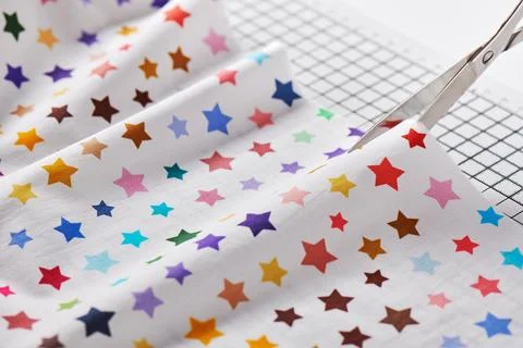 Process cutting fabric with a pattern of colorful stars by scissors on craf.. Stock Photos