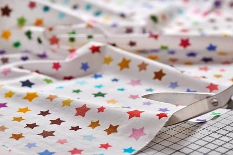 Process cutting fabric with a pattern of colorful stars by scissors on craf.. Foto stock