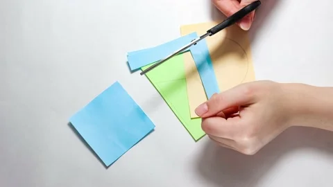 The process of cutting geometric shapes out of paper with scissors. Stock Footage 152753894
