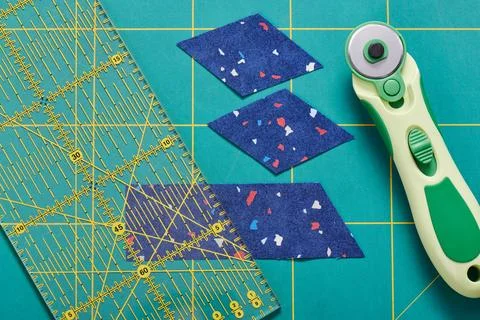 The process of cutting pieces of fabric in the shape of diamonds to create .. Stock Photos