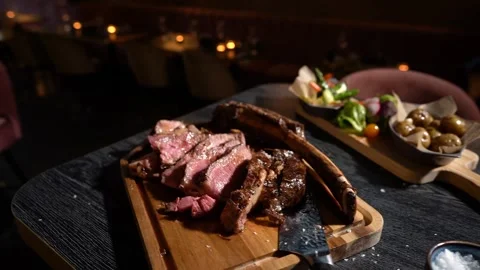 Process of cutting the steak with a large kitchen knife on a cutting board. Stock Footage 261461617