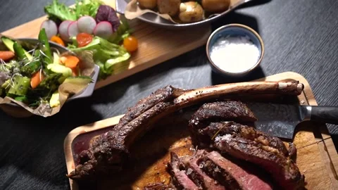 Process of cutting the steak with a large kitchen knife on a cutting board. Stock Footage 261461650