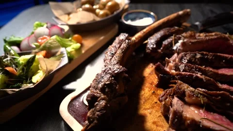 Process of cutting the steak with a large kitchen knife on a cutting board. Stock Footage 261461743