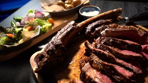 Process of cutting the steak with a large kitchen knife on a cutting board. Stock Footage 261461771