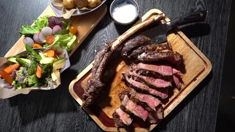 Process of cutting the steak with a large kitchen knife on a cutting board. Stock Footage 261461807
