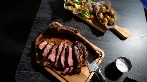 Process of cutting the steak with a large kitchen knife on a cutting board. Stock Footage 261461938