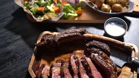 Process of cutting the steak with a large kitchen knife on a cutting board. Stock Footage 261834400