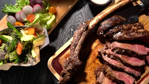 Process of cutting the steak with a large kitchen knife on a cutting board. Stock Footage 261834438