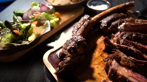 Process of cutting the steak with a large kitchen knife on a cutting board. Stock Footage 261834511