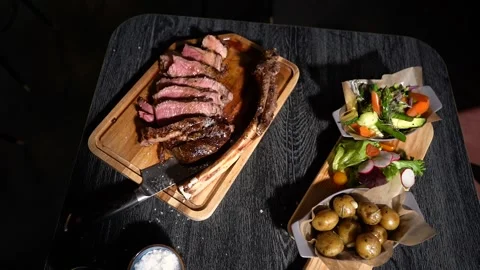 Process of cutting the steak with a large kitchen knife on a cutting board. Stock Footage 262055738