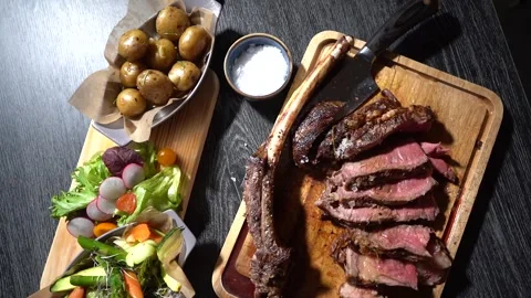 Process of cutting the steak with a large kitchen knife on a cutting board. Stock Footage 262055833