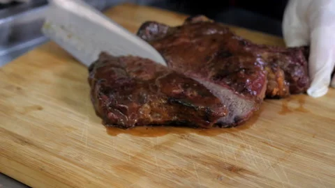 Process of cutting tomahawk steak with a large knife on wooden board Stock Footage 144788875