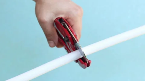 The process of cutting a white plastic pipe with a red pipe cutter Stock Footage 338005670