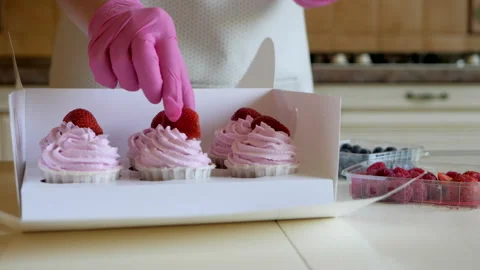 The process of decorating pink cupcakes with fresh strawberries. Stock Footage 144558403