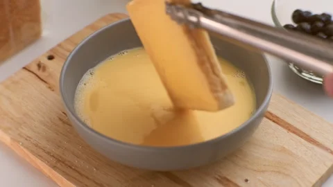 Process of dipping the bread in the egg to fry in the pan. Fried bread slices Stock Footage 242565197
