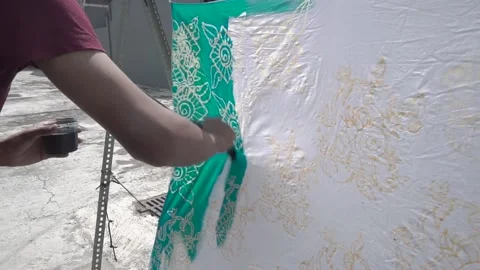The process of dyeing the cloth that has been coated with wax (malam) with dye Stock Footage 146742558